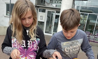 Zwei Kinder löffeln Kürbisse aus