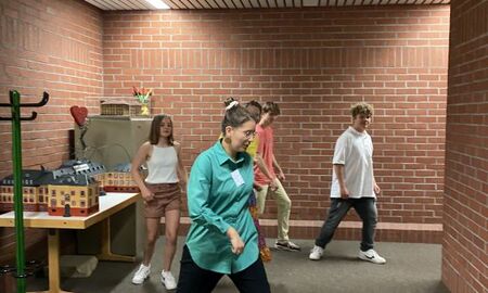 Eine Lehrerin tanzt etwas vor und vier Jugendliche tanzen nach
