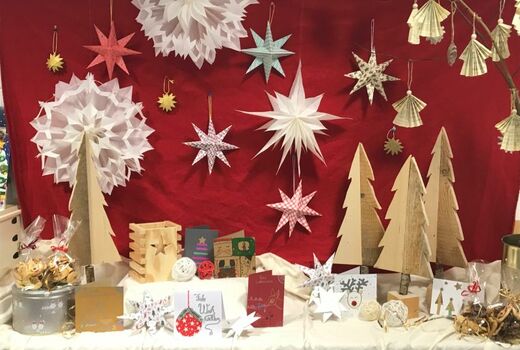 Ein geschmückter Tisch voll mit weihnachtlichen Dingen: Plätzchen, Karten, Sterne, Engel und kleine Holz-Weihnachtsbäume