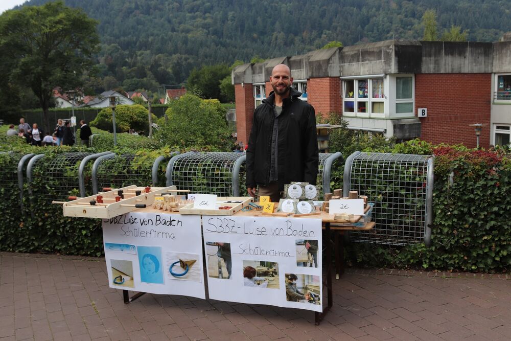 Ein Mann steht lächelnd am Verkaufsstand der Schülerfirma des SBBZ Luise von Baden.