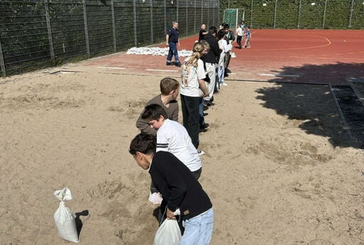 Schüler bilden eine Kette und geben Sandsäcke weiter