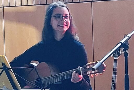 eine Schülerin lächelt und spielt Gitarre