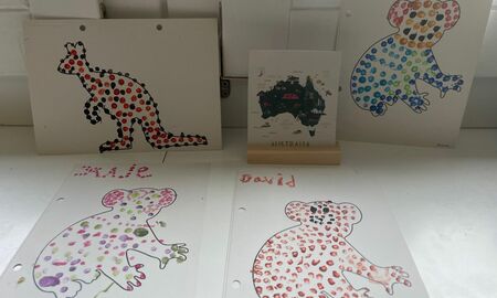 Auf einer Fensterbank liegen und stehen Punktebilder zu Tieren in Australien wie Koalas und Kängurus. Eine Bildkarte zur Australien steht in einem Aufsteller.