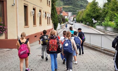 Eine Schülergruppe läuft mit Rucksäcken einen Weg neben dem Hotel Schloßberg herunter. Rechts führt eine Straße vorbei.