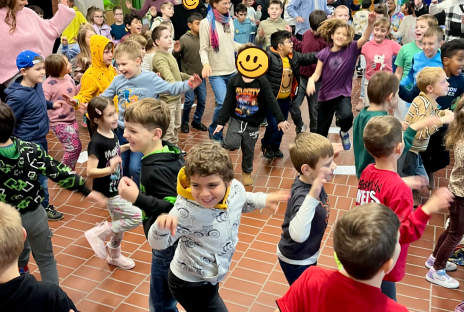 Viele Kinder der Grundschule Sprache machen Sport. Sie stehen auf einem Bein und strecken beide Arme aus.