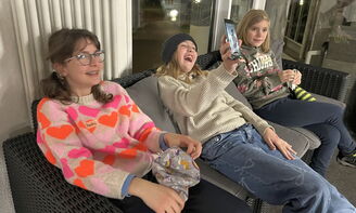 Drei Mädchen lachen über ihre winterliche Kopfbedeckungen