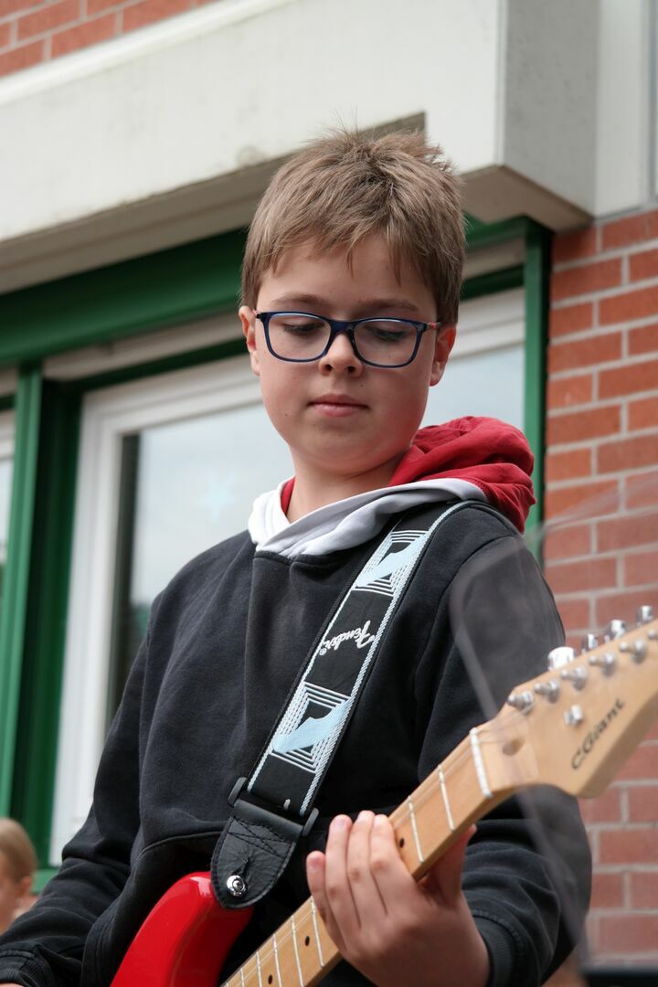 Ein Junge spielt mit der E-Gitarre.