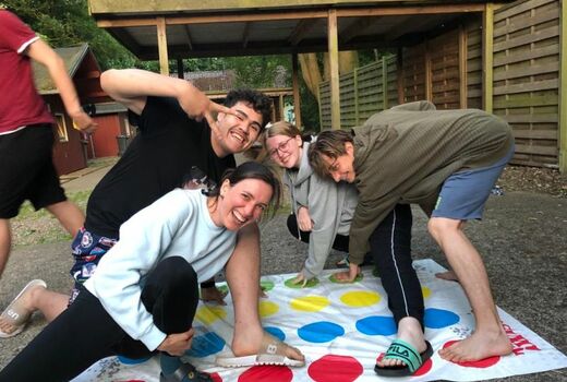 Drei Jugendliche und eine Lehrerin spielen Twister und haben dabei einen Riesenspaß.