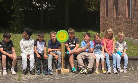 Kinder warten an einem Haltestellenschild