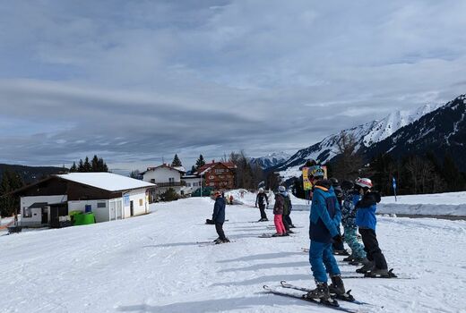 Ein paar Skifahrer stehen im flachen Bereich der Piste und warten, dass es losgeht.