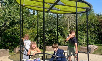Vier Kinder fahren Karussell und lachen in die Kamera.
