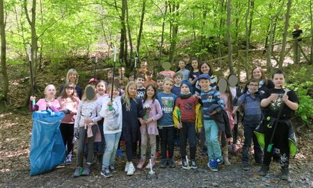 Gruppenfoto  im Wald von zwei dritten Klassen mit ihren Lehrerinnen und alle sind mit Handschuhen, Müllzangen und Mülltüten ausgestattet.