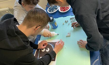 Drei Jungen machen ein Mosaik aus Computer-Tastaturblöcken