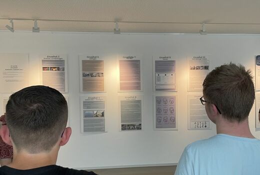 Zwei Schüler stehen vor einer Informationswand und lesen die Plakate.