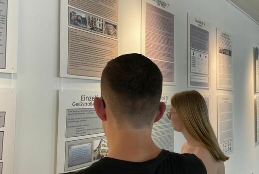 Ein Schüler und eine Schülerin stehen vor der Informationswand und lesen die Plakate.
