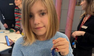 Ein Mädchen hält einen fertigen Schlüsselanhänger in die Kamera