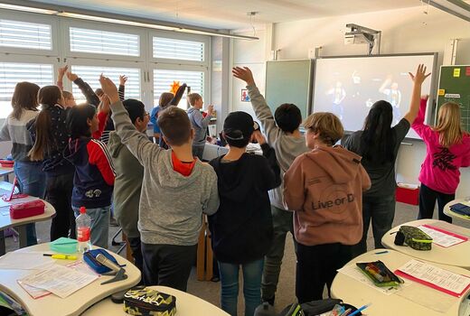 Mädchen tanzen vor einem Multimediaboard