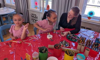 Erwachsene basteln mit Kleinkindern am Tisch