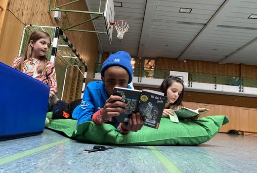 Kinder lesen auf einer Matte Bücher