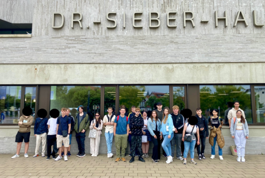 Schülerinnen und Schüler der Jahrgangsstufe 1 und 2 stehen vor der Dr.-Sieber-Halle in Sinsheim.