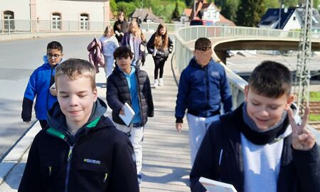 Die Schülerinnen und Schüler der vierten Klasse laufen über eine Brücke gemeinsam zurück zur Schule.