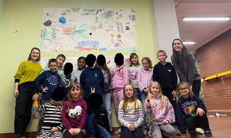 Eine Gruppe von Schülerinnen und Schülern und zwei Lehrerinnen lächeln in die Kamera. Zwei Schülerinnen halten Flaschen mit Kindersekt nach oben.