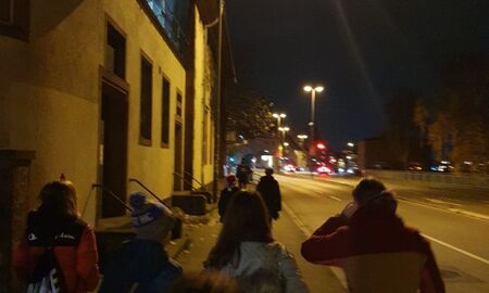 Eine Gruppe Jugendlicher läuft am Abend am alten Karlstorkino vorbei. Man sieht sie von Hinten,