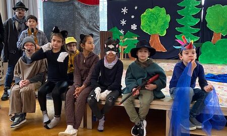 Kinder in Kostümen zum Musikstück "Peter und der Wolf" sitzen am Bühnenrand