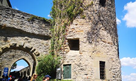 Zwei Lehrerinnen stehen mit Schülerinnen und Schülern im Eingang der Burg Guttenberg und schauen über die Mauer hinunter