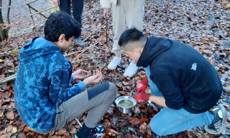 Schülerinnen und Schüler entzünden ein Feuer