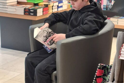 Ein Junge liest ein Buch in einem Sessel.