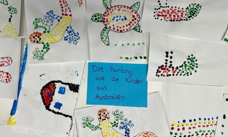 Bunte Punktbilder verschiedener Tiere oder Gegenstände liegen um einen Zettel mit der Aufschrift: Dot-Painting - wie die Kinder aus Australien.