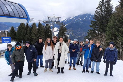 Gruppenfoto mit den Schülern und einer Lehrkraft im Schnee. Im Hintergrund ist der Lift.