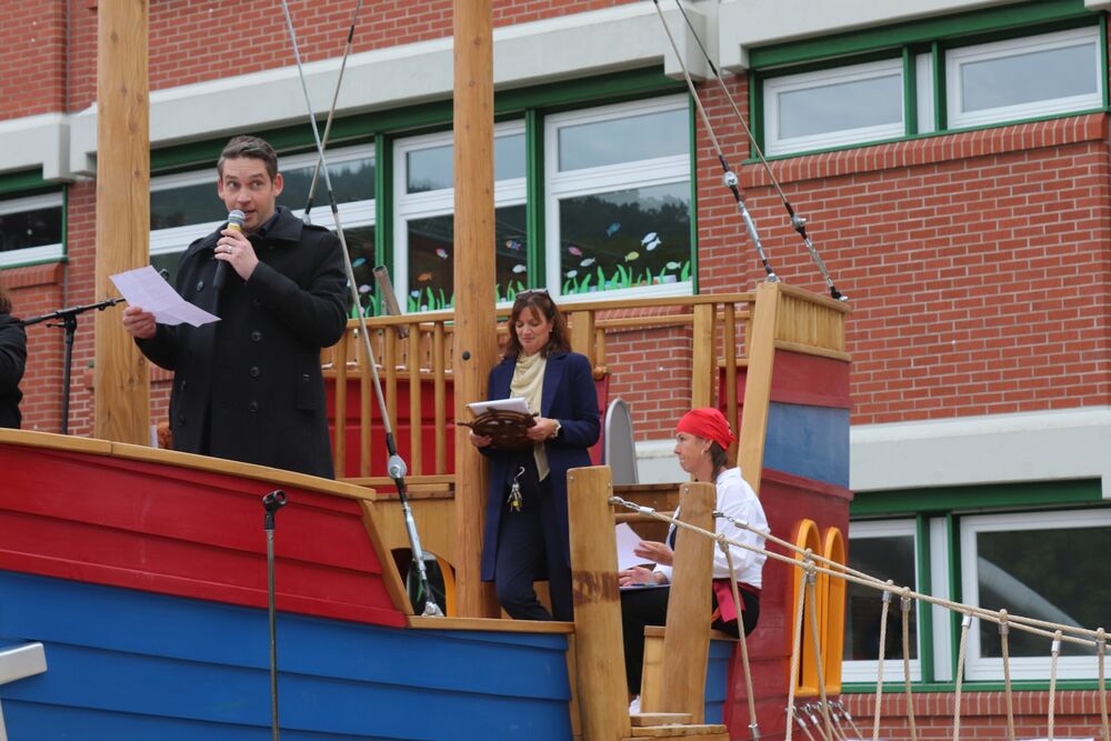 Ein Mann hält auf dem Schiff stehend eine Rede.