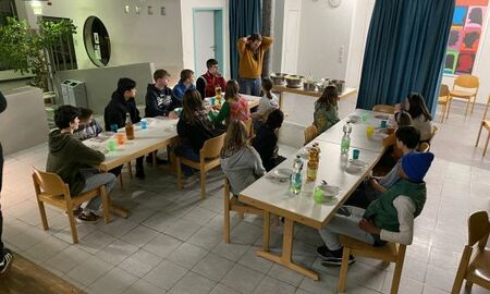 Eine Gruppe sitzt beim Abendessen an zwei Tischreihen