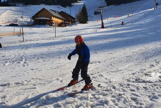 Ein Kind fährt Ski auf einem sonnigen Hang