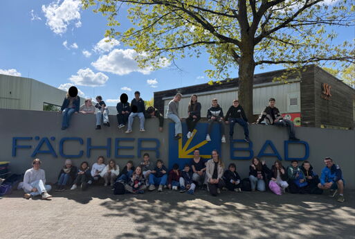 Viele Kinder und Lehrkräfte der Luise sitzen vor und auf dem Schild vom Fächerbad