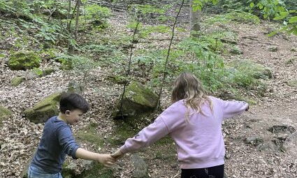 Kinder testen eine Brücke über den Bach