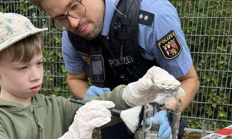 Ein Polizist nimmt mit einem Kind Spuren vom Tatort
