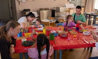 Erwachsene basteln mit Kleinkindern am Tisch