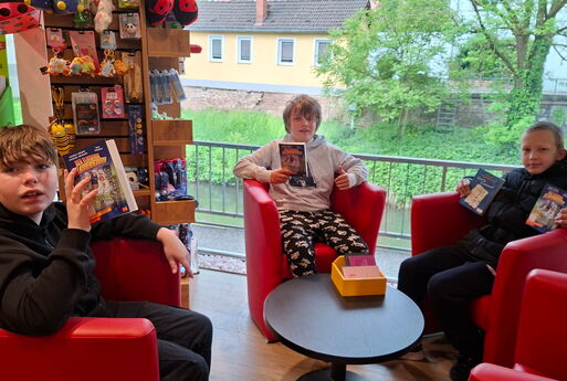 Drei Jungs aus der Klasse mit dem neuen Buch in einem Sessel.