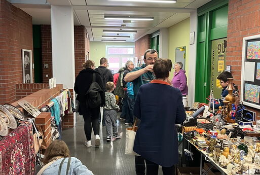 Mehrere Verkaufsstände auf einem Flur und Menschen die sich Sachen anschauen