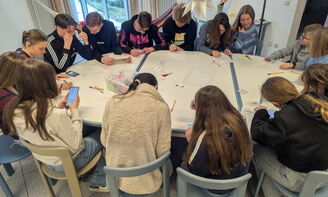 Die Jugendlichen sitzen gemeinsam am Tisch und basteln