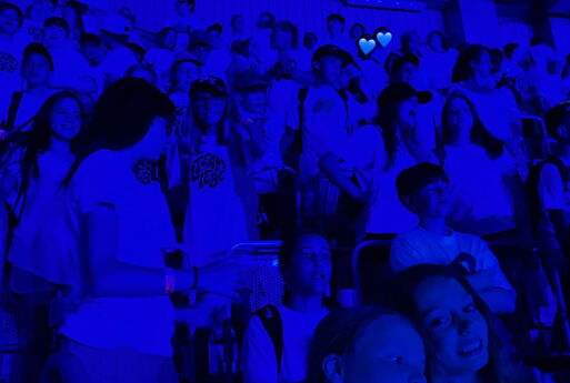 SchülerInnen umarmen sich bei blauem Licht und singen
