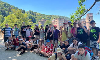 Ein Gruppenfoto von Kindern, im Hintergrund ist Wald und ein Teil des Schlosses von Heidelberg zu sehen