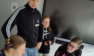 Eine Gruppe Jugendlicher arbeitet an einem Plakat