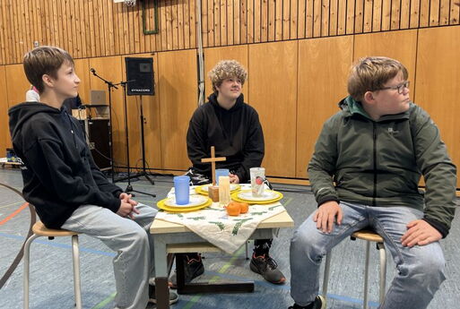 Drei Schüler sitzen an einem gedeckten Tisch