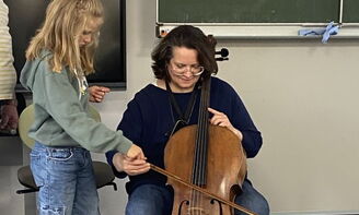 Ein Mädchen streicht mit dem Bogen über das Cello